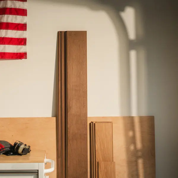 Full-length Flooret planks leaning against a plywood workshop wall in afternoon light